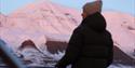 Silhouette of a person onboard a boat. snowcovered mountains in the background