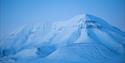 Snow-covered mountain, with blue tones coloring the mountain.