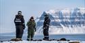 Ekspedisjonsdeltakere står foran frossen fjord og fjell