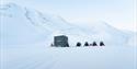 Snowmobiles parked next to a wilderness cabin
