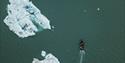 A drone view of a small boat near floating ice.