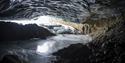 A guide and two guests inside a dark ice cave