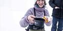 A guide offering something hot to drink in a cup and cookies during a break on a trip