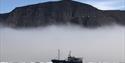 Boat in front of a mistcovered mountain