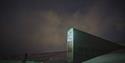 A person standing in front of the entrance to the Svalbard Global Seed Vault in the darkness