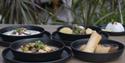 Four food dishes in bowls on a table