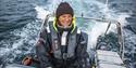 A smiling guide sailing a RIB boat across a fjord