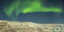 Northern lights under a dark sky above a large glacier