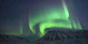 Nordlys som skinner på himmelen over et fjell