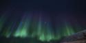 Nordlys som skinner på himmelen over et fjell