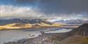 Bygningene i Longyearbyen i forgrunnen med et overskyet fjellandskap i bakgrunnen