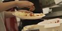 A person putting food on a plate before serving