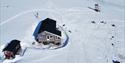 An overview picture of two cabins, on the snow-covered tundra.