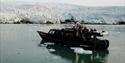 A boat with guests on board sailing in a bay with a glacier in the background