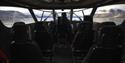 The inside of the boat MS Kvitbjørn with passenger seats in the foreground, the captain in the driver's seat and a view towards mountainous landscapes