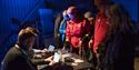 Persons surrounding a table of event merchandise at a concert