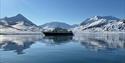 Båt ligger i havet foran et Arktisk landskap