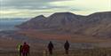 People walking down from a mountain with rivers and mountains in the background