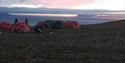 a campsite during summer at Svalbard on a mountain. Sunset to be in the horizon behind the fjord.