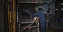 A guest on a guided tour of Mine 3 having a look at the forge inside the mine