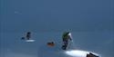 Two people skiing with sleds in the dark at Svalbard