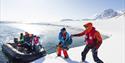 A rubber boat lands in a winter landscape. The boat carries people and skis.
