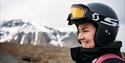 Woman smiling with helmet on. Mountains in the background.