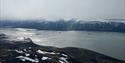 Longyearbyen sett fra den andre siden av fjorden. Adventfjorden i front, og Longyearbyen og omkringliggende fjell i bakgrunnen.