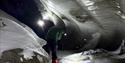 Two persons with headlamps inside an ice cave.