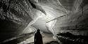 Person standing inside an ice cave with a head lamp