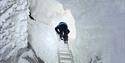 A person is climbing on a ladder at the entrence of the ice cave.