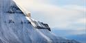 A snowy mountain with cloudy skies in the background