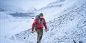 A person walking up a mountain in the winter.