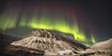 Rarely powerful northern lights shining over a mountain