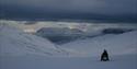 Person on a snowmobile on their way down a hill