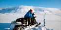 A man on a snowmobile who is ice fishing