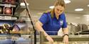 An employee in Svalbardbutikken's fresh produce section preparing their cheese counter