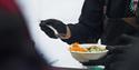 A person putting food in a bowl before serving it to a guest