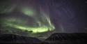 Green northern lights above the mountains