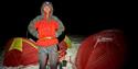 A person standing between two tents during the winter at Svalbard