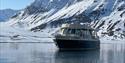 Båt ligger i havet foran et Arktisk landskap