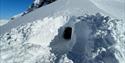 Picture of the entrence to a snow cave in the sun