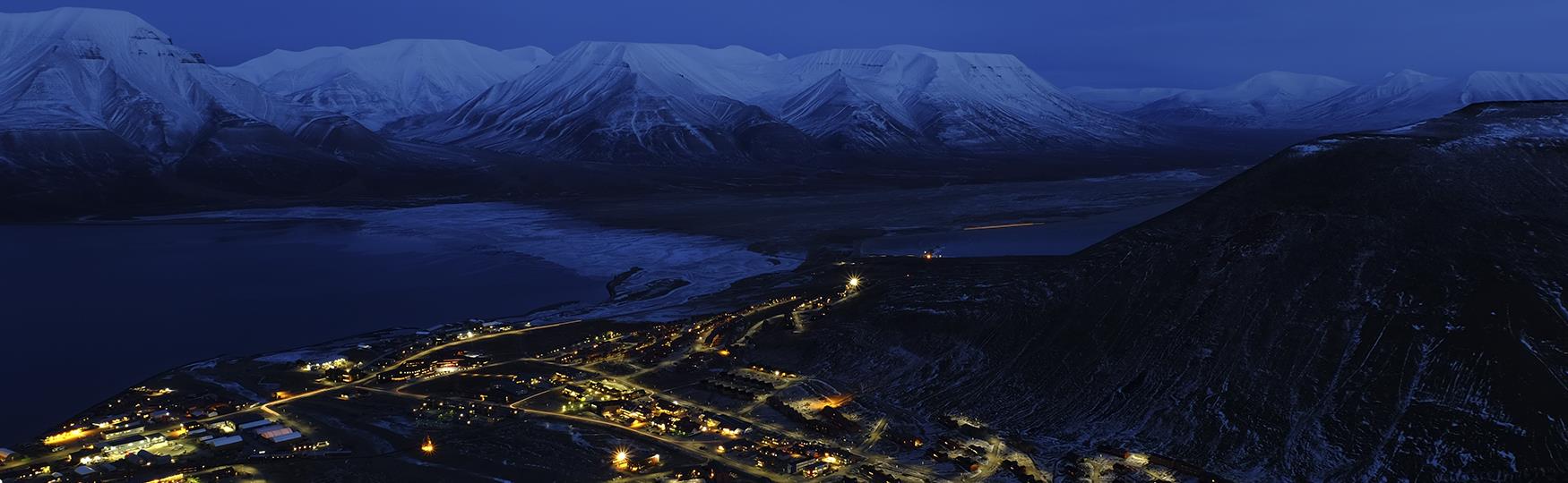 Longyearbyen sett ovenfra i blått lys med fjell i bakgrunnen