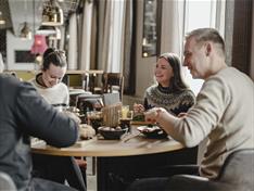 Fire personer sittende rundt et restaurantbord som spiser og prater sammen