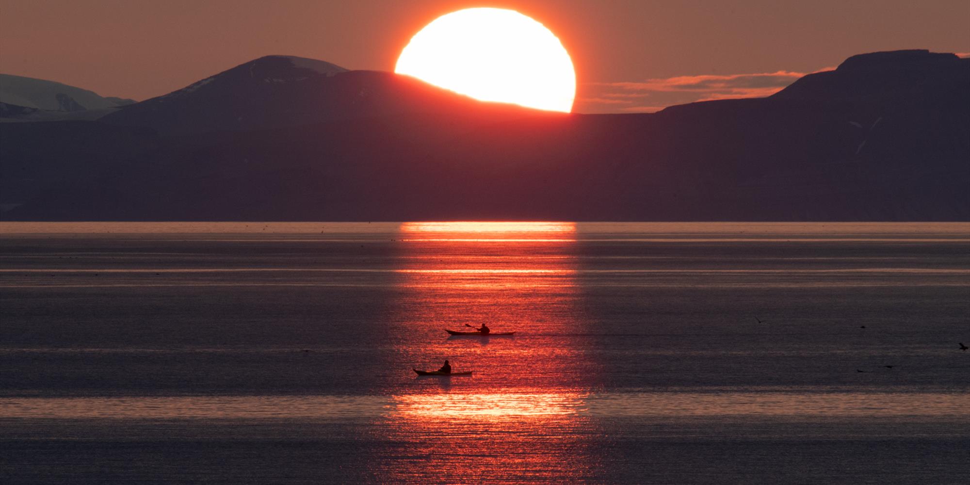 Two persons kayaking in the sunset on the ocean