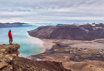A person on top a cliff looking down on Pyramiden
