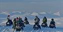 A tour group on snowmobiles having a stop to enjoy the view