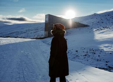 Person in the strong winter sun. The Seedvault is seen in the background. 