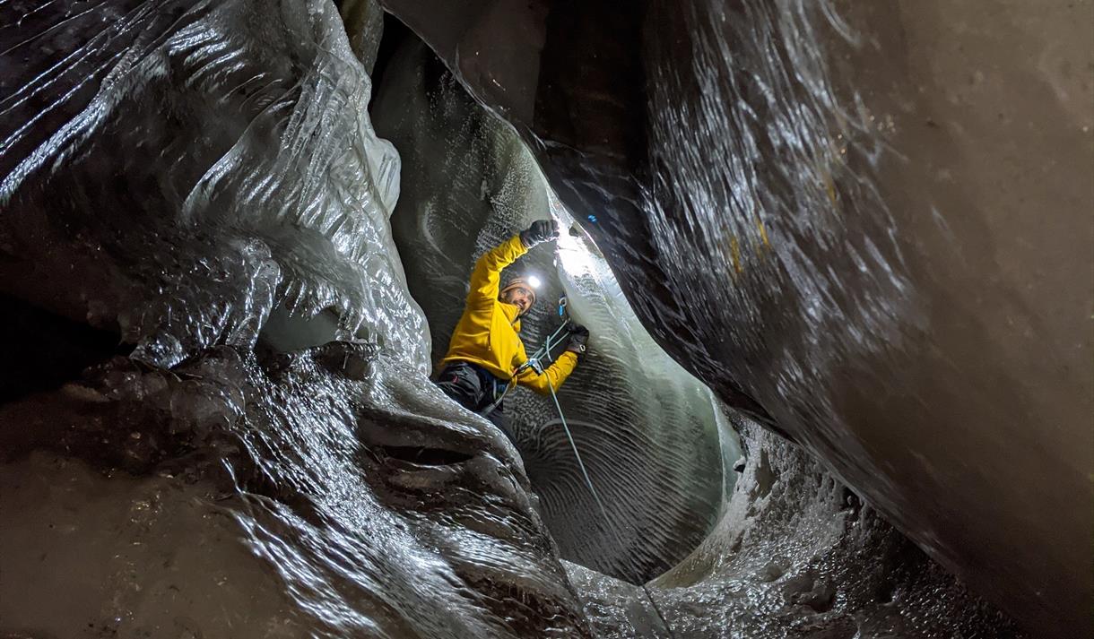 A person climbing inside an ice cave