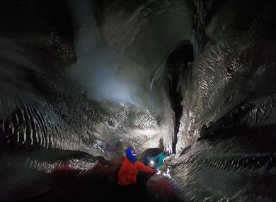Guests exploring an ice cave with hedlamps on
